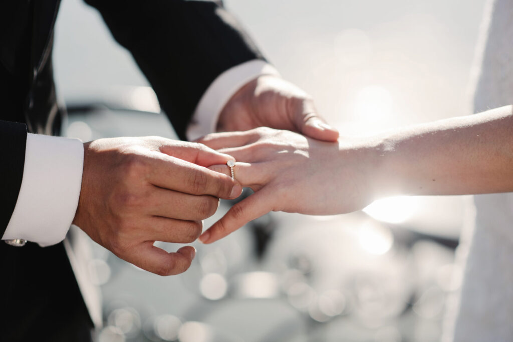 bride and groom holding hands during ring exchange part of an outdoor wedding ceremony